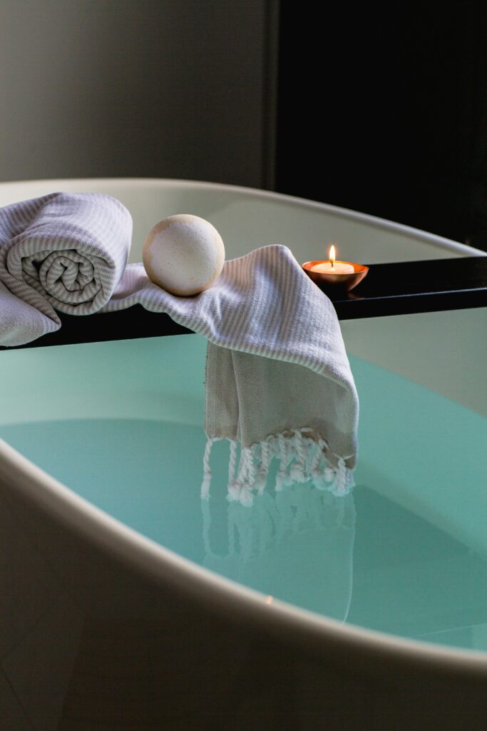 pexels-photo-374148-374148 Elegant indoor spa setting with bathtub, candle, towel, and bath bomb for relaxation.